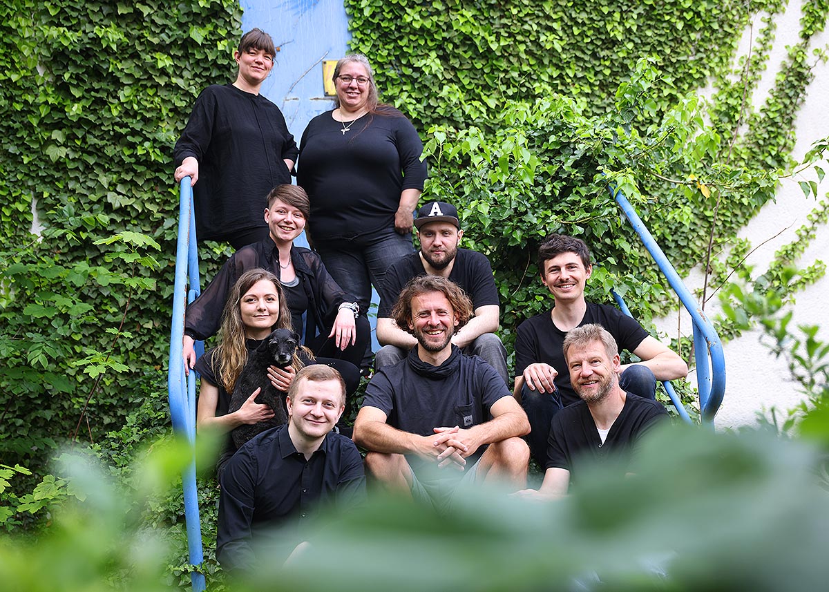 Teamfoto recable, Mitarbeiter sitzen auf Efeu-bewachsener Treppe, Moodfoto